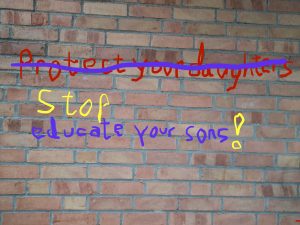 Bild einer Mauer mit Graffity darauf, die teilweise durchgestrichen und mit Worten ergänzt wurde. Statt 